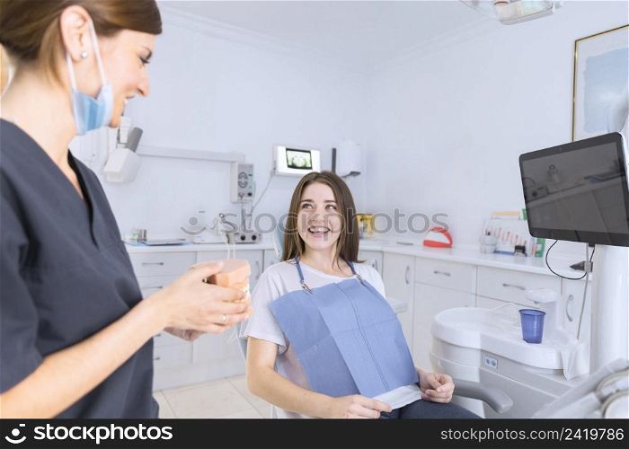 female dentist showing teeth model smiling patient