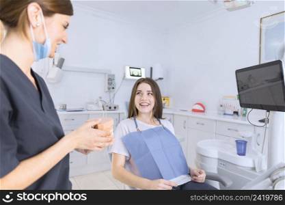 female dentist showing teeth model smiling patient