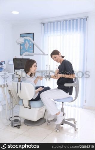 female dentist showing teeth model smiling patient clinic