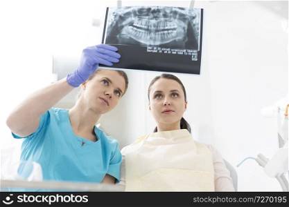Female dentist showing x-ray to woman at dental clinic