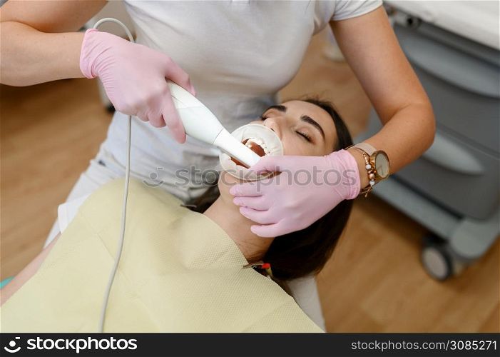 Female dentist works with patient tooth in clinic, stomatology. Doctor in uniform, medical worker, medicine and health, professional teeth care, dentistry. Female dentist works with patient tooth in clinic
