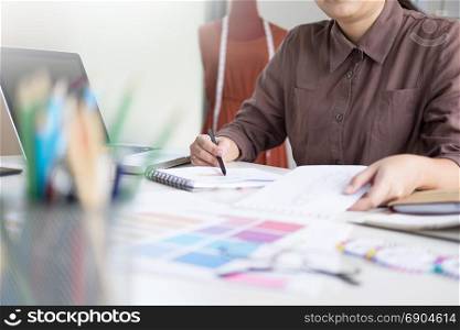 female designer choosing colour on pantone for her fashion design in workplace office
