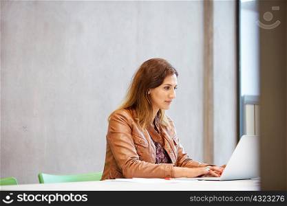 Female designer typing on laptop in design studio