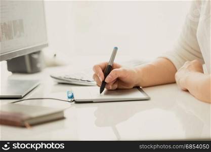 Female designer using digital graphic tablet while working on computer