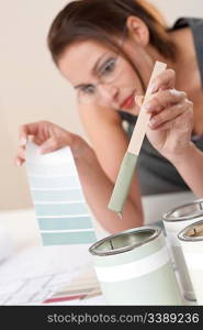 Female designer with can of paint choosing color at office