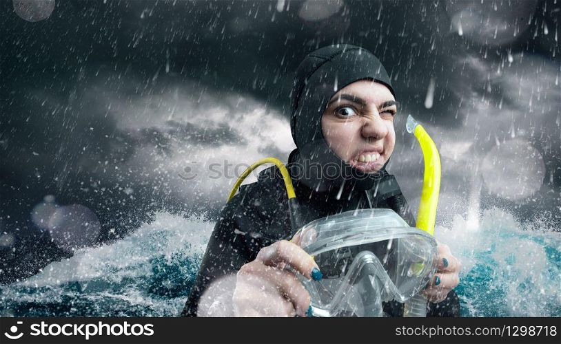 Female diver in wetsuit and diving gear in the ocean in bad weather. Frogman on the beach, underwater sport