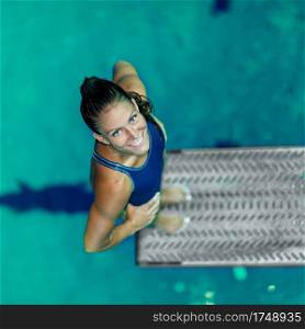 Female diver standing on the jumping board. Preparing to jump into the pool