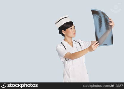 Female doctor analyzing x-ray report over light blue background