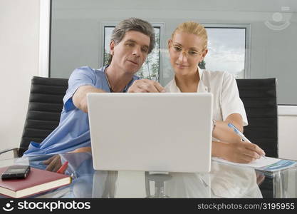 Female doctor and a male surgeon sitting in front of a laptop