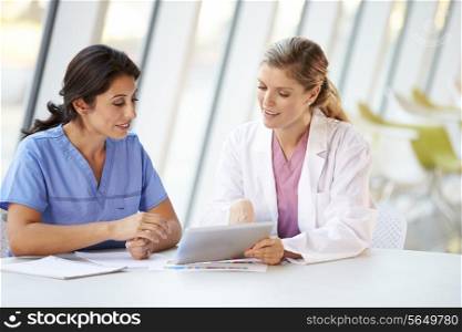 Female Doctor And Nurse Having Meeting In Hospital Canteen