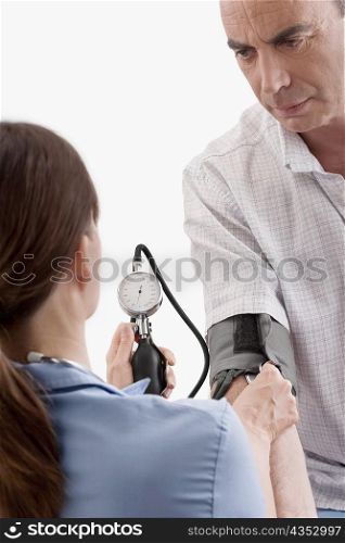 Female doctor checking blood pressure of a mature man