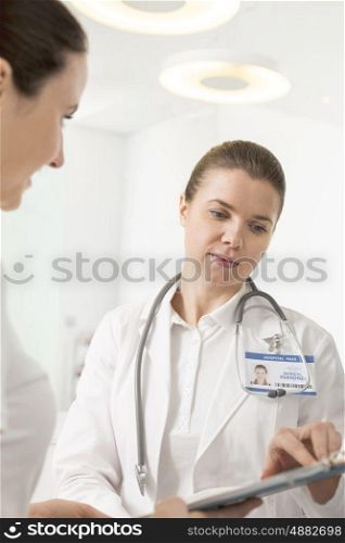 Female doctor discussing with assistant over clipboard at hospital
