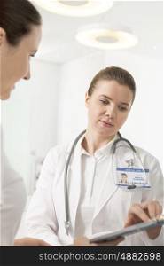 Female doctor discussing with assistant over clipboard at hospital