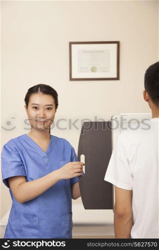 Female Doctor Examining Male Patient&rsquo;s Mid Section With X-ray Machine