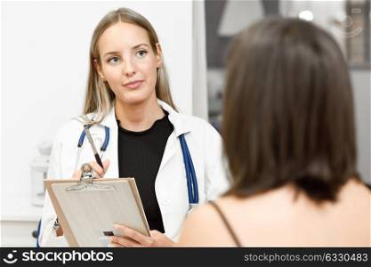 Female doctor explaining diagnosis to her patient. Brunette woman having consultation with blonde girl in medical office.