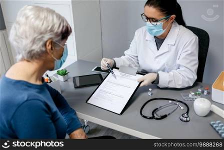 Female doctor explaining to her patient the consent form to coronavirus vaccine