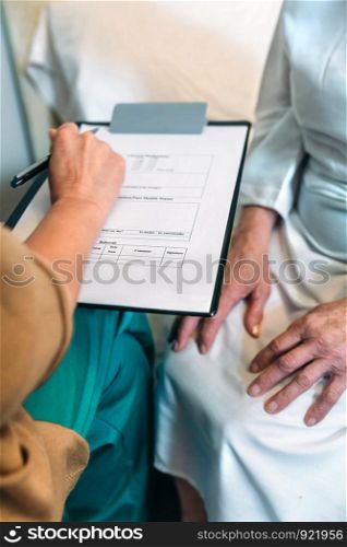 Female doctor filling out a questionnaire to a senior patient. Female doctor filling out a questionnaire