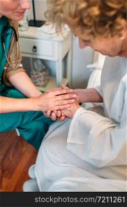 Female doctor giving encouragement to elderly patient by holding her hands. Doctor giving encouragement to elderly patient
