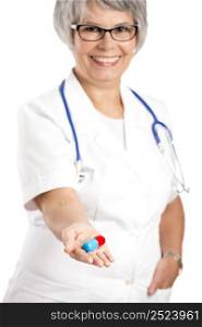 Female doctor holding a a big pill, isolated on white