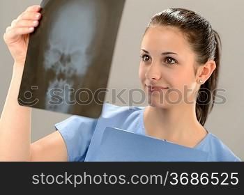Female doctor holding and examining X-ray picture with skull