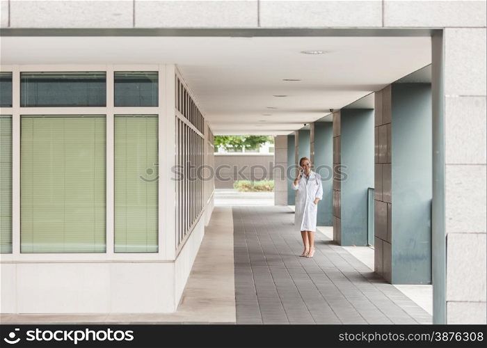 Female doctor is phoning while walking in the hospital building