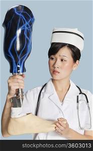 Female doctor looking at prosthesis foot over light blue background