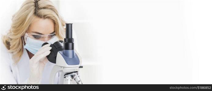 Female doctor looking through a microscope. Female doctor in protective glasses and mask looking through a microscope, studio shot isolated on white background