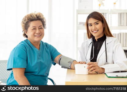 Female doctor measuring blood pressure of senior woman elderly at examination room in hospital clinic.