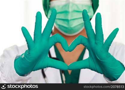 Female doctor medical mask and hands in latex glove shows the symbol of the heart