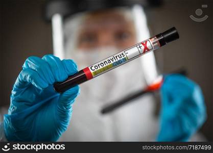 Female Doctor or Nurse Holding Test Tube of Blood Labeled Positive for Coronavirus COVID-19 Disease.