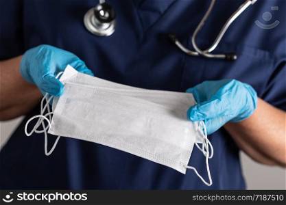 Female Doctor or Nurse Wearing Surgical Gloves Holding A Few Medical Face Masks.