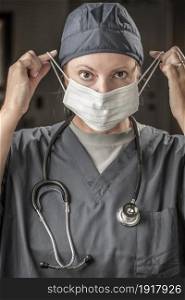 Female Doctor or Nurse with Stethoscope Putting On Protective Face Mask .