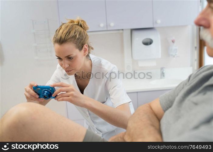 female doctor photographing patients leg