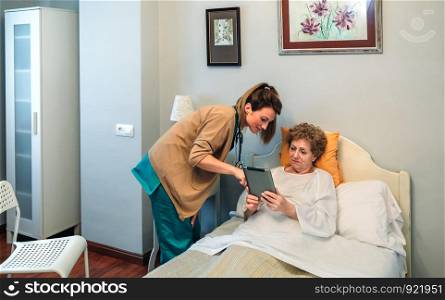 Female doctor showing results of a medical test on the tablet to female senior patient. Female doctor showing results of a medical test on the tablet