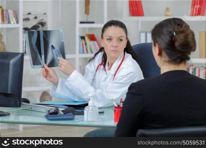 female doctor showing something to her patient on x-ray image