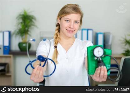 female doctor showing stethoscope and blood meassuring tool