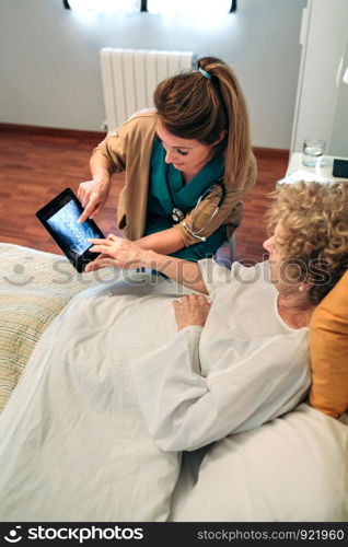 Female doctor showing to female senior patient an x-ray on the tablet. Female doctor showing an x-ray on the tablet