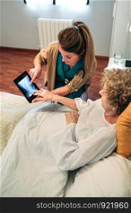 Female doctor showing to female senior patient an x-ray on the tablet. Female doctor showing an x-ray on the tablet