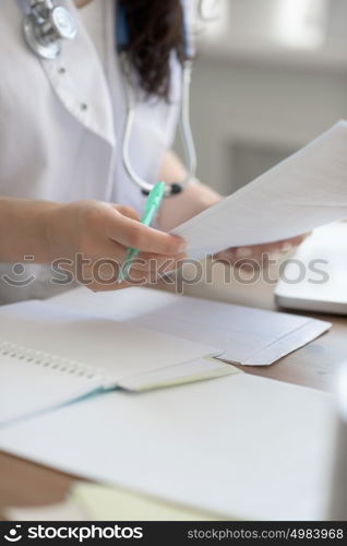 Female doctor taking notes during looking at patient medical tests at her office