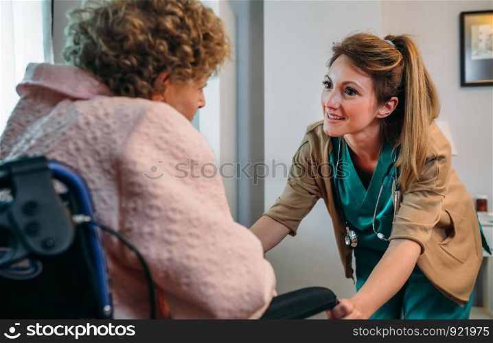 Female doctor talking to elderly female patient in a wheelchair. Doctor talking to elderly patient in a wheelchair