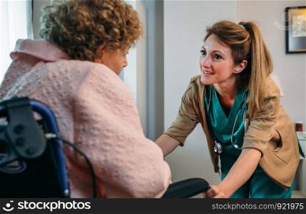 Female doctor talking to elderly female patient in a wheelchair. Doctor talking to elderly patient in a wheelchair