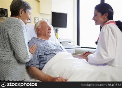 Female Doctor Talking To Senior Couple In Hospital Room