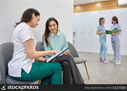 Female doctor talking to teen patient in hallway. Medical checkup, healthcare appointment in clinic. Doctor talking to teen patient in hallway