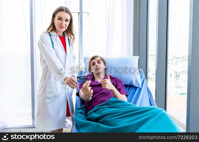 Female doctor therapeutic advising and a man patient on bed show holding a credit card lying in the room hospital background,payment medical