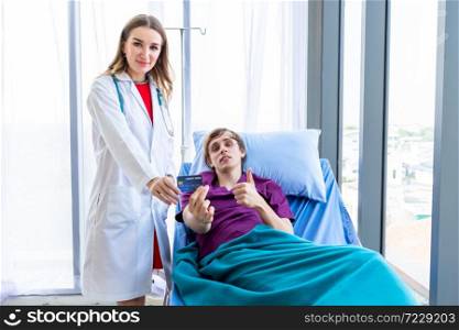 Female doctor therapeutic advising and a man patient on bed show holding a credit card lying in the room hospital background,payment medical