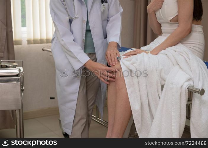 Female doctor used two hands to hold patient knee for check up bone injuries. Health care and insurance concept