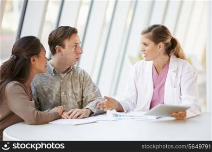 Female Doctor Using Digital Tablet Talking With Patients