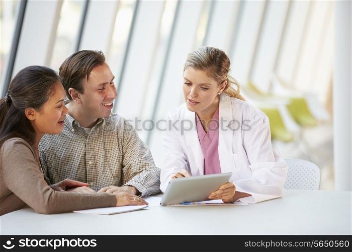 Female Doctor Using Digital Tablet Talking With Patients