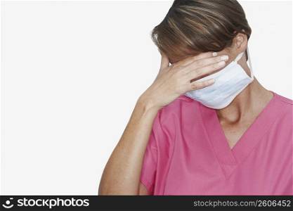 Female doctor wearing a surgical mask with hand over eyes