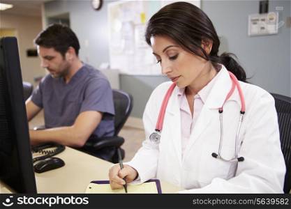 Female Doctor With Male Nurse Working At Nurses Station